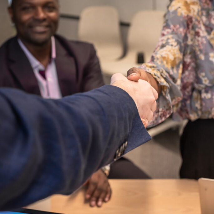 Business man shake hands with business women agreeing on partnerships or introducing themselves for first time meet.